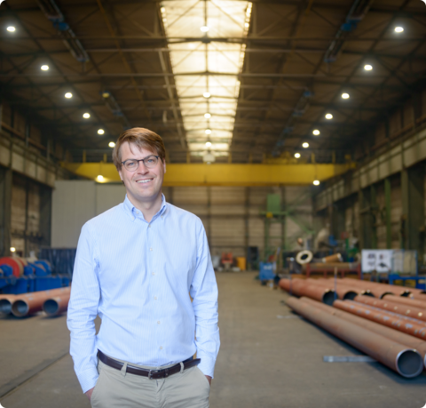 Mann mit Brille lächelt in die Kamera, im Hintergrund sieht man eine Lagerhalle | © Antje Schimanke/Gedankenwerft