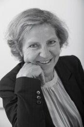 Portrait einer Frau, die mit ihren Kopf gestützt auf den Arm in die Kamera lächelt | © BIS/Jens Meier