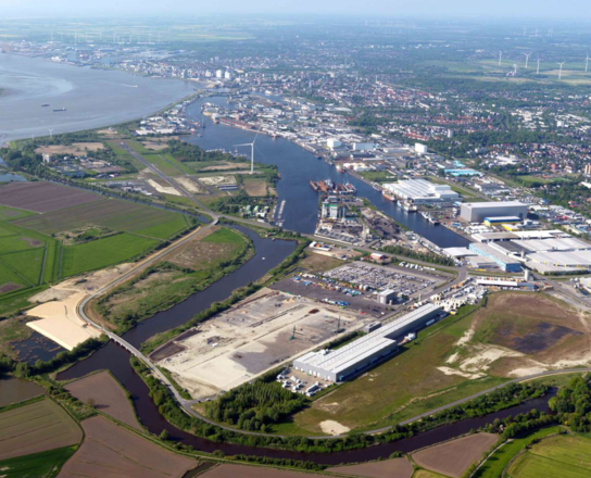 Aufsandung des Initialclusters im LUNEDELTA | © BIS/Scheer Luftansicht einer Stadt am Wasser und einer Baustelle im Vordergrund | © BIS/Scheer